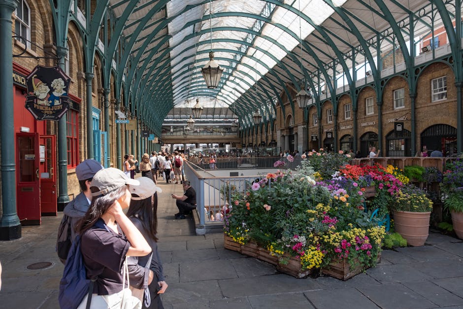 A detailed view of an arched glass and metal roof structure in an indoor marketplace or shopping arcade, with multiple rows of curved teal-colored metal beams supporting large rectangular glass panels